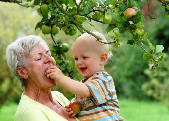 Grandmother with child under apple tree
